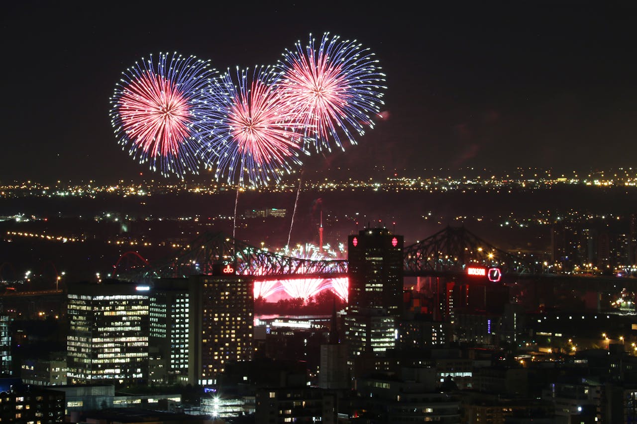Breathtaking fireworks display illuminating Montreal's skyline and iconic Jacques Cartier Bridge during a festive night.